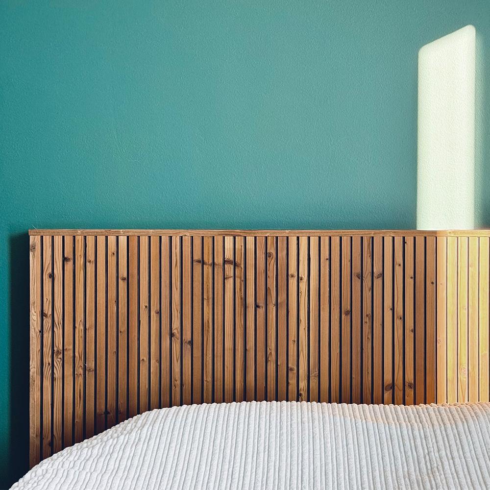 A headboard made from Sola decorative panels. thermally modified paired with a green hue on the wall.